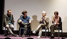 Stephane Brize (second from the right) speaking in French in Buenos Aires in 2019. Seated to his left, the interpreter (on the extreme right) waits to translate into Spanish. Stephane Brize in Buenos Aires in 2019.jpg