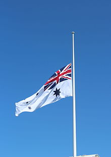 The Australian White Ensign flying at half-mast. In accordance with British tradition, the flag is flying only one flag's width below the top of the pole. AU NavalEnsignHalfMast.JPG
