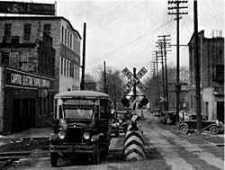 Lansing, Mich., street scene about 1930. Note the brick pavement, railroad warning device and the municipal bus.