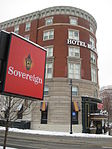 Boston Hotel Buckminster at intersection of Beacon Street and Brookline Avenue in Kenmore Square; Sovereign Bank and Pizzeria Uno signs also visible