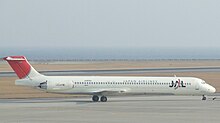 Sebuah pesawat McDonnell Douglas MD-81 sedang menaiki landasan, dengan warna kelabu melihat Pemandangan Laut di latar belakang