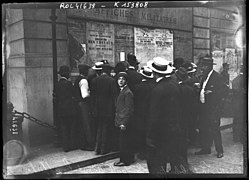Photo noir et blanc avec hommes attroupés devant une affiche.