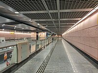 A corridor where the Art-in-Transit artwork is located along. There is also a view of the station platform on the bottom left corner.