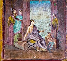 Female painter sitting on a campstool and painting a statue of Dionysus or Priapus onto a panel which is held by a boy. Fresco from Pompeii, 1st century Wall painting - female painter - Pompeii (VI 1 10) - Napoli MAN 9018.jpg