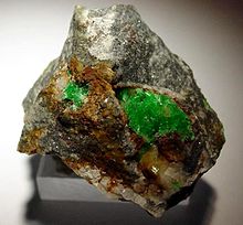 ярко-зеленые кристаллы в двух кластерах на бело-серой скале