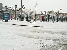 Photographie en couleurs de plusieurs arrêts de bus sous la neige.