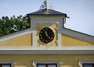 Huvudbyggnadens fronton med klocka.