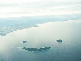 Une vue aérienne des îles de Mamutik (en haut à gauche), de Sulug (en haut à droite) et de Manukan (au centre) ressemblant à un visage souriant.