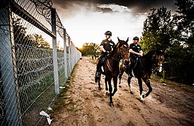 Mounted police patrol the border barrier