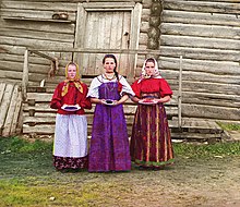 Young Russian peasant women in front of a traditional wooden house (c. 1909 to 1915), photograph taken by Prokudin-Gorskii Prokudin-Gorskii-08.jpg