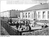 Lek i ei sandkasse ved en barnehage i Eisenhüttenstadt 1954. Eisenhüttenstadt var den første planlagte «sosialistiske byen» i Øst-Tyskland. Byen het opprinnelig Stalinstadt og ble anlagt med bolig- og fritidsområder tilknyttet stålverket der.