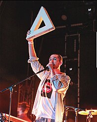 En bild på Dan Smith, sångare i bandet Bastille på en konsert i Ungern 2019. På bilden håller han upp en bokstav ur bandets logga.