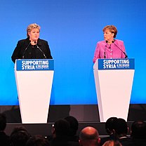 Norway's Prime Minister Erna Solberg (left podium) and Germany's Chancellor Angela Merkel (right podium) address the Supporting Syria and the Region press conference.