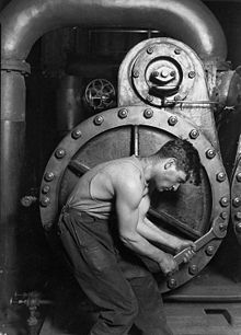 Lewis Hine, 1920. Meccanico di una centrale elettrica al lavoro su una pompa a vapore in una rappresentazione iconica della mascolinità.