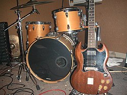 Instrumentos musicais utilizados no rock and roll; à esquerda, a bateria, e, à direita, a guitarra elétrica.