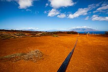 Irrigation tubing running along the red dirt of Kahoʻolawe as a crew works to plant new life in the hard packed soil