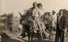 two women smiling while riding a donkey