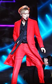 Taemin performs on stage in a bright red suit.