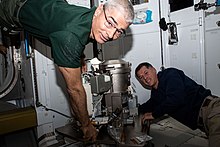 Expedition 65 Flight Engineers Mark Vande Hei (from left) and Shane Kimbrough partner together for orbital plumbing tasks as they install a new toilet inside the International Space Station's Tranquility module. Astronauts Mark Vande Hei and Shane Kimbrough work on a new toilet.jpg