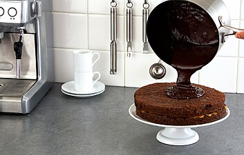 Chocolate ganache being poured onto a cake