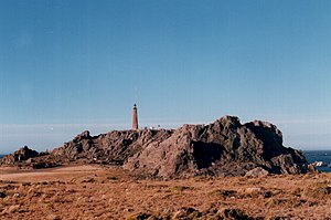 Vista de Cabo Blanco desde el sur. Se observa también el Faro Cabo Blanco (foto tomada en enero de 1999).