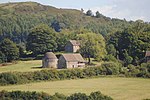 a group of stone buildings amongst farmland and forests