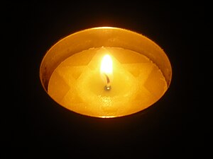 English: A lit Yom Hashoah candle in a dark ro...