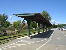 A railway platform with a green metal shelter