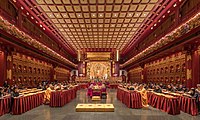 Praying monks and nuns in the temple with laypeople seated behind them in the Hundred Dragon Hall