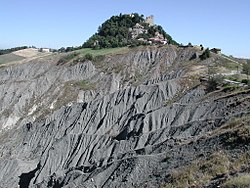 Pemandangan Rock of Canossa dengan reruntuhan benteng yang tampak di atasnya