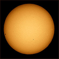 The sun photographed through a telescope with special solar filter. Sunspots and limb darkening are clearly seen at the image