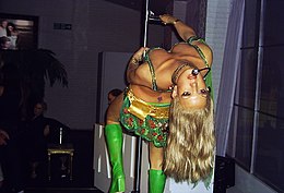 Spears Leaning backwards from a revolving pole with her "I'm a Slave 4 U" outfit