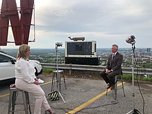 Senator Tommy Tuberville being interviewed outside at WBRC in 2021, with the neon "W" in the station's landmark bluff sign seen to the left. Tommy Tuberville at WBRC in 2021 01.jpg
