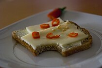 Sebuah roti lapis terbuka standar dari roti lapis keju ditaburi dengan potongan cabai merah