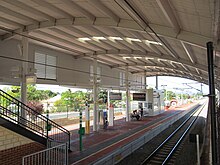 View of station platform under large shelter covering the platform and tracks