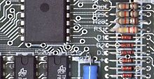 Part of a 1984 Sinclair ZX Spectrum computer board, a printed circuit board, showing the conductive traces, the through-hole paths to the other surface, and some electronic components mounted using through-hole mounting PCB Spectrum.jpg