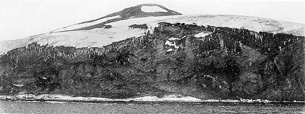 Photograph of a sea cliff with a hill behind