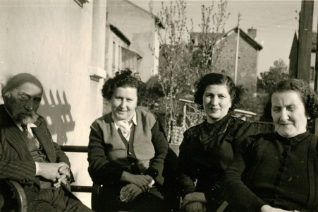 Photographie en noir et blanc d'un homme et de trois femmes assis sur une terrasse.