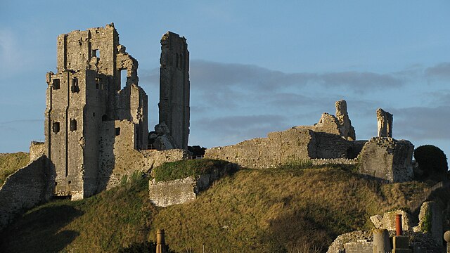 The shattered remains of a stone building, with two walls of a tower standing higher above the ruins.