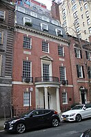 A brick townhouse with slate roof and semicircular entrance portico