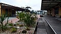 Southbound view after grade separation works, with the original station platform buildings and with new station in background, March 2021