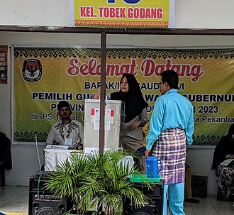 A voter submitting her ballot at a polling station in Pekanbaru, Riau Indonesian local elections 2018 - voting in Pekanbaru cropped.jpg