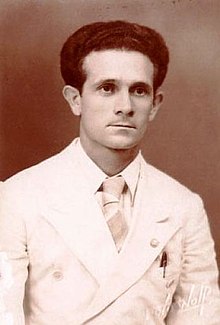 Black and white portrait of Pierats in a white suit and tie