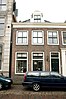 Huis met twee schilddaken, een brede lijstgevel en aan de straat twee dakkapellen met gebogen fronton en zijvoluten