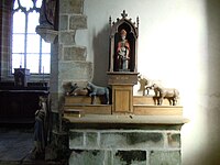 Retable, statue de Saint Eloi ferrant un cheval et ex-voto de chevaux en bois.