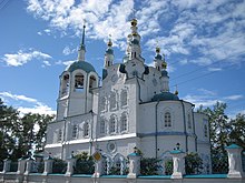 Photographie en contre-plongée d'un bâtiment religieux de type cathédral blanc avec des toits bleus où se trouvent des croix orthodoxes.