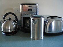 two electric kettles, a drip coffee maker, and a toaster on a table top