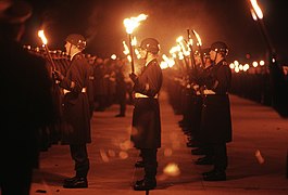 The uniform of the Grand Tattoo notably still uses the Stahlhelm DF-ST-88-08721 Members of the German military carry lit torches in honor of General (GEN) Charles L. Donnelly Jr. 1987.jpeg