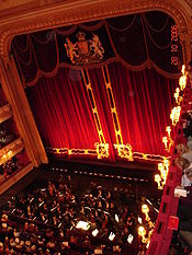 interior of a traditional nineteenth century theatre, with red plush curtains and much gilt decoration