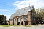 Three bay nave and chancel. No side aisles. Side entry porch and small belfry. Slate roof. Walls dressed stone, brick dressings. Wooden windows. School house/parish hall of similar materials. Built 1861. Type of site: Church. Current use: Religious – Church.